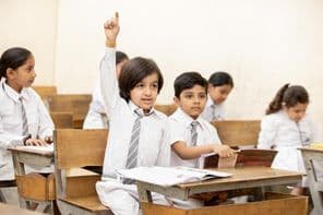खुश भारतीय स्कूल बच्चा हाथ उठाता हुआ